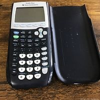 Front view of TI-84 Plus calculator with cover removed and placed beside it, showing keypad and screen.