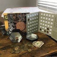 Front view of coin books (including Lincoln Cent 1975-2013), coins spread out on table, and coin holders visible.