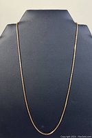 Full length of 18-inch gold chain on display bust