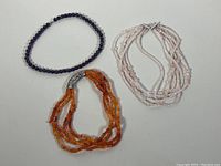 Full view of all three chokers showing bead types and strand counts.