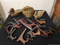 All three vintage bird sculptures with multiple wooden easel display stands on black tablecloth