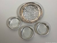 Top-down view of the three round sterling silver coasters with cut crystal centers and one oval sterling silver dish with cut crystal base.