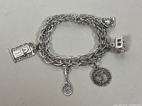 Sterling silver charm bracelet with five unique charms: a door, tennis racket, ornate 'J', sun, and birdcage.