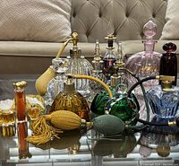 Group view of 10 perfume bottles and atomizers on glass table
