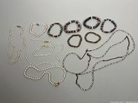 Full set of white and multicolored freshwater pearl jewelry including necklaces and bracelets laid on gray background.