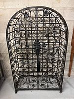 Front view of black wrought iron wine rack with locking doors and decorative grape and leaf motifs