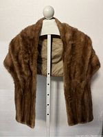 Full front view of vintage mink fur stole displayed on a white mannequin showing the brown fur and the beige lining inside.