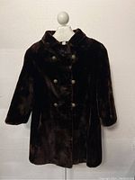 Full view of coat on mannequin showing overall design, double-breasted front and mid-thigh length.