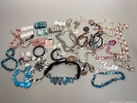 Overhead photo showing entire lot of assorted mother of pearl and abalone shell jewelry pieces including chokers, bracelets, necklaces, earrings, and bangles.