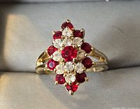 Front view of gold plated ring showing red and clear stones cluster