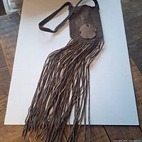 Top view displaying the entire length of the brown suede purse and its very long fringe extending from the bottom.