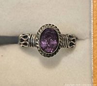 Top-down view of sterling silver ring with oval amethyst set in detailed band.