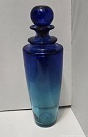 Photo of two-toned blue glass decanter approx 14" tall with a dark blue stopper.