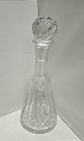 Clear crystal decanter with a round stopper, diamond cut pattern on body and stopper. Approximately 12 inches tall.