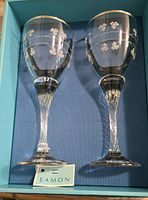 Pair of Eamon wine glasses with silver rims decorated with claddagh motif, displayed in original blue Eamon box.