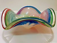 Glass table centerpiece viewed from side showing wavy colorful edges and swirled interior.