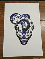 Photo of an Indigenous style blue and white print on white paper, detailed art with symmetrical shapes and motifs.
