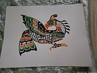 Photo of an unsigned art print of a Thunderbird in traditional Indigenous style, laid flat on a fabric surface.