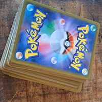 Stack of Pokémon trading cards faced down showing the backs with Poké Ball design.