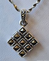 Close-up of the sterling silver pendant showing nine black pyramid-shaped stones arranged in a 3x3 grid, with a decorative bail stamped 925.