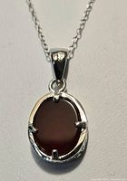 Close-up of oval red agate pendant set in sterling silver with four prongs.