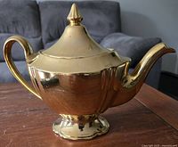 Photo showing the exterior of the gold-tone Royal Winton teapot with pointed lid and curved handle and spout.
