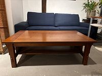 Front view of the large wooden coffee table with visible lower shelf and legs.