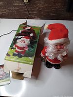Photo showing the toy standing next to its original box, box has detached flaps and some wear
