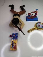 Top view of the 1987 Regency Crawling Cowboy toy laid flat with three reproduction tin toys on white background.