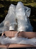 Three large clear plastic sheeting tubes partially unrolled, placed outside on grass.