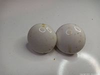 Front view of two white porcelain door knobs showing dome shape and minor discoloration.