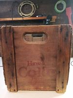 Front side of the wooden Coca-Cola advertisement box showing faded text 'Have a Coke' and cut-out handle.