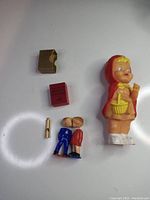 Overview of all items: Stalwood Red Riding Hood figurine, magnetic kissing couple, two mini Webster's dictionaries, small train whistle.
