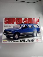 Front of box showing blue GMC Jimmy SUV model image and branding of Super Snap 1/20 scale.