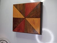 View of the top lid of the wooden box showing the geometric triangular pattern in reddish, yellow, and brown wood tones.