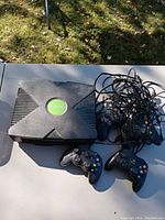 Photo of Original Xbox console and four controllers on table outdoors