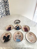 Lot of 7 oval Bradford Exchange collector's plates featuring various portraits of Princess Diana, arranged on a patterned white lace tablecloth.