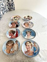 Lot of 8 Bradford Exchange Princess Diana collector plates displayed on a lace tablecloth, showing varied portraits and formal wear.
