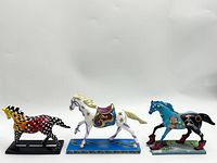 Photo showing the three Trail of Painted Ponies horse figurines together in profile view, highlighting their distinctive painted designs.