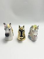 Three unicorn head figurines shown front and center with white background, including one gold, one pastel mane and one rainbow mane unicorn.