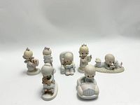Seven Precious Moments figurines arranged on white background