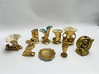 Photo showing the entire lot of nine gold-finished ceramic pieces arranged in a line on a white background.