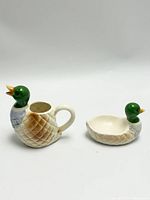 Two ceramic duck collectibles, one pitcher and one bowl, photographed from the front and side.