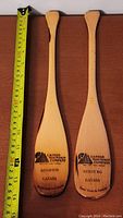Pair of miniature canoe paddles with measurement tape showing approx. 10 inches long.