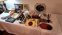 Wide view of the full collection on a table showing various framed pictures, plates, and utensils