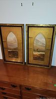 Pair of framed cathedral-shaped Highland prints showing frames and prints in full.