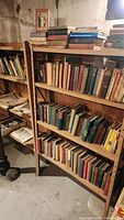 Wide view of wooden shelves filled with old books and newspapers stacked and lined up, showing the extensive quantity in the lot.