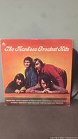 Full album cover showing the autographed vinyl record "The Monkees Greatest Hits" with signatures of band members in blue ink.