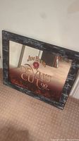 Frontal angled photo of the Jim Beam Devil's Cut mirror showing the wooden brick-like frame, the mirror surface with logo and fire graphic.