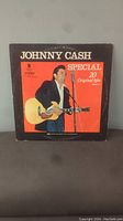 Front cover of the Johnny Cash vinyl album. Black and red background with photo of Johnny Cash playing guitar and text 'Special 20 Original Hits'.